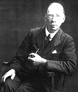 Black-and-white portrait photograph of a man in a suit holding a pipe.